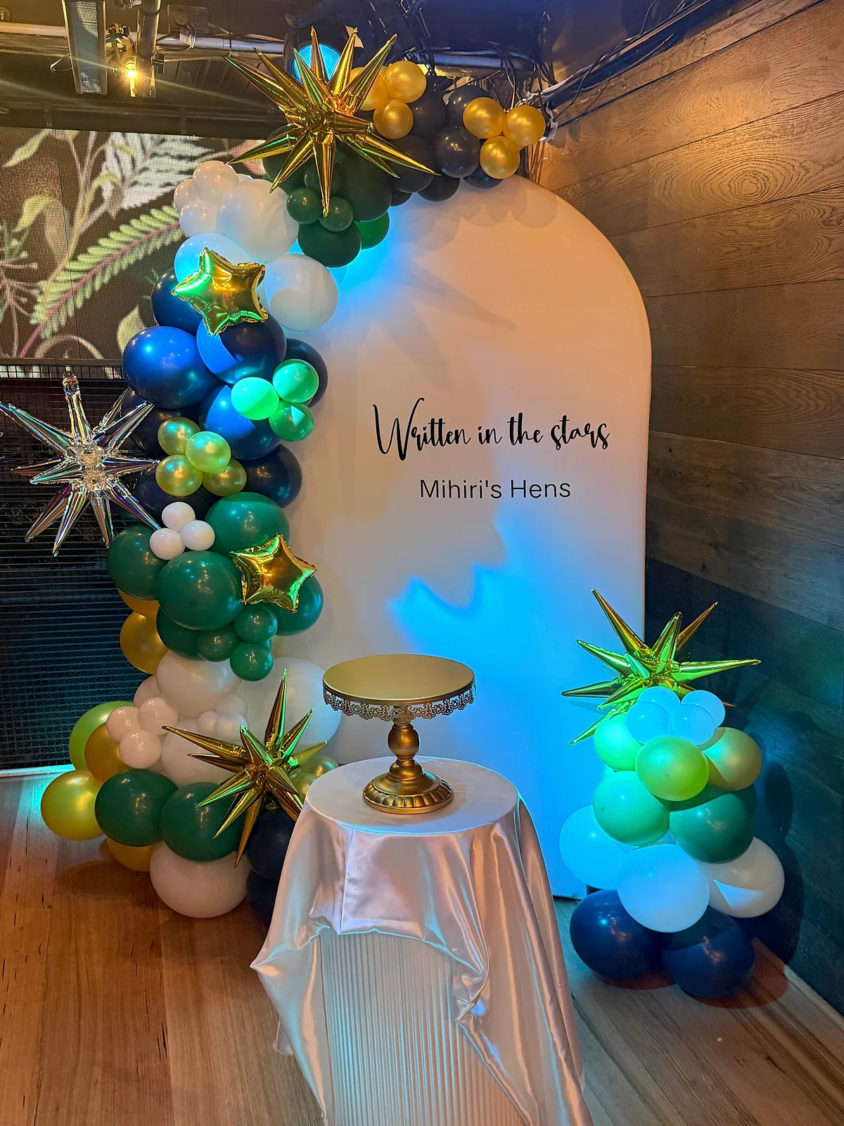 Written in the Stars hens party backdrop in Melbourne CBD with blue and green balloons, metallic stars and a gold cake stand.